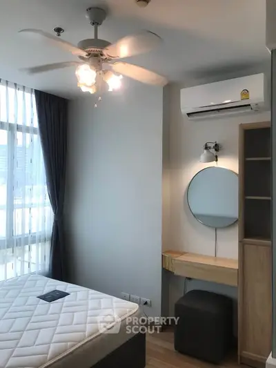 Modern bedroom with natural light, featuring a ceiling fan, air conditioning, and stylish furnishings.