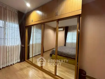 Spacious bedroom with mirrored wardrobe and large windows for natural light.