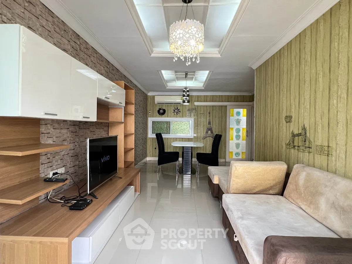 Modern living room with stylish decor and open dining area, featuring elegant lighting and contemporary furniture.