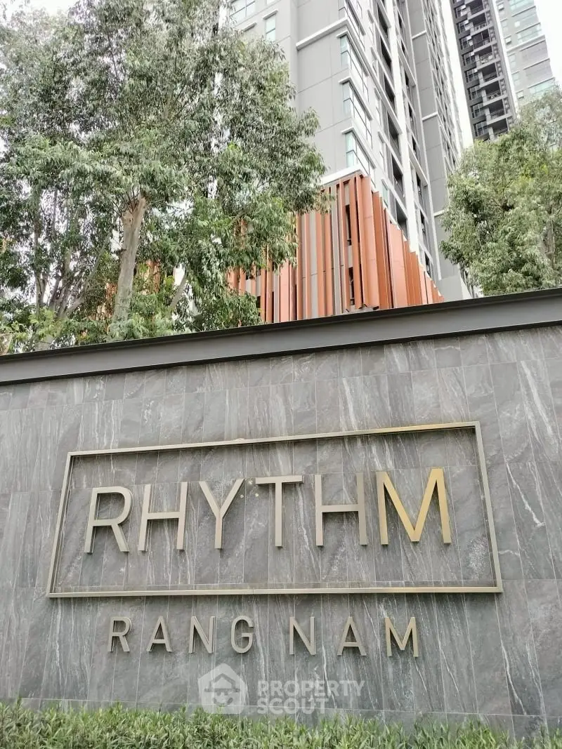 Modern high-rise building exterior with lush greenery at Rhythm Rang Nam.