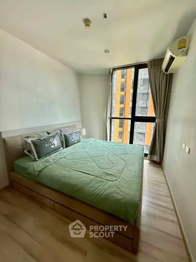 Modern bedroom with large window and green bedding in a high-rise apartment.