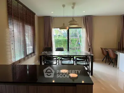 Spacious dining area with modern decor and large windows overlooking greenery.