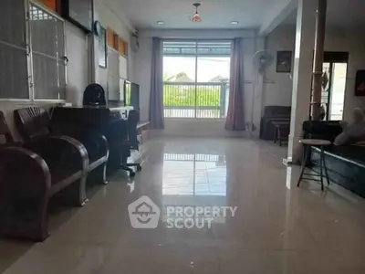 Spacious living room with large window and polished tile flooring, perfect for natural light and comfort.