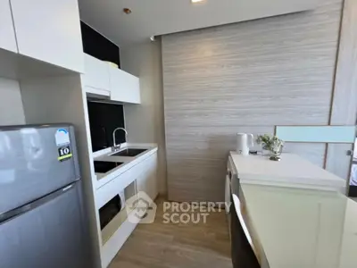 Modern kitchen with sleek white cabinetry and stainless steel appliances in a stylish apartment.