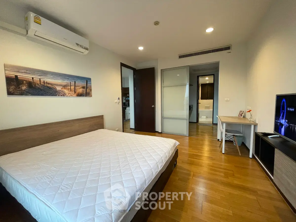 Spacious bedroom with modern decor and wooden flooring in a stylish apartment.