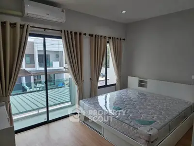 Modern bedroom with large window and balcony view, featuring a comfortable bed and air conditioning.