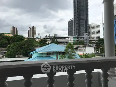 Stunning urban view from balcony with city skyline and lush greenery.