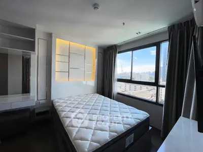Modern bedroom with large window offering city view, featuring a stylish bed and built-in storage.
