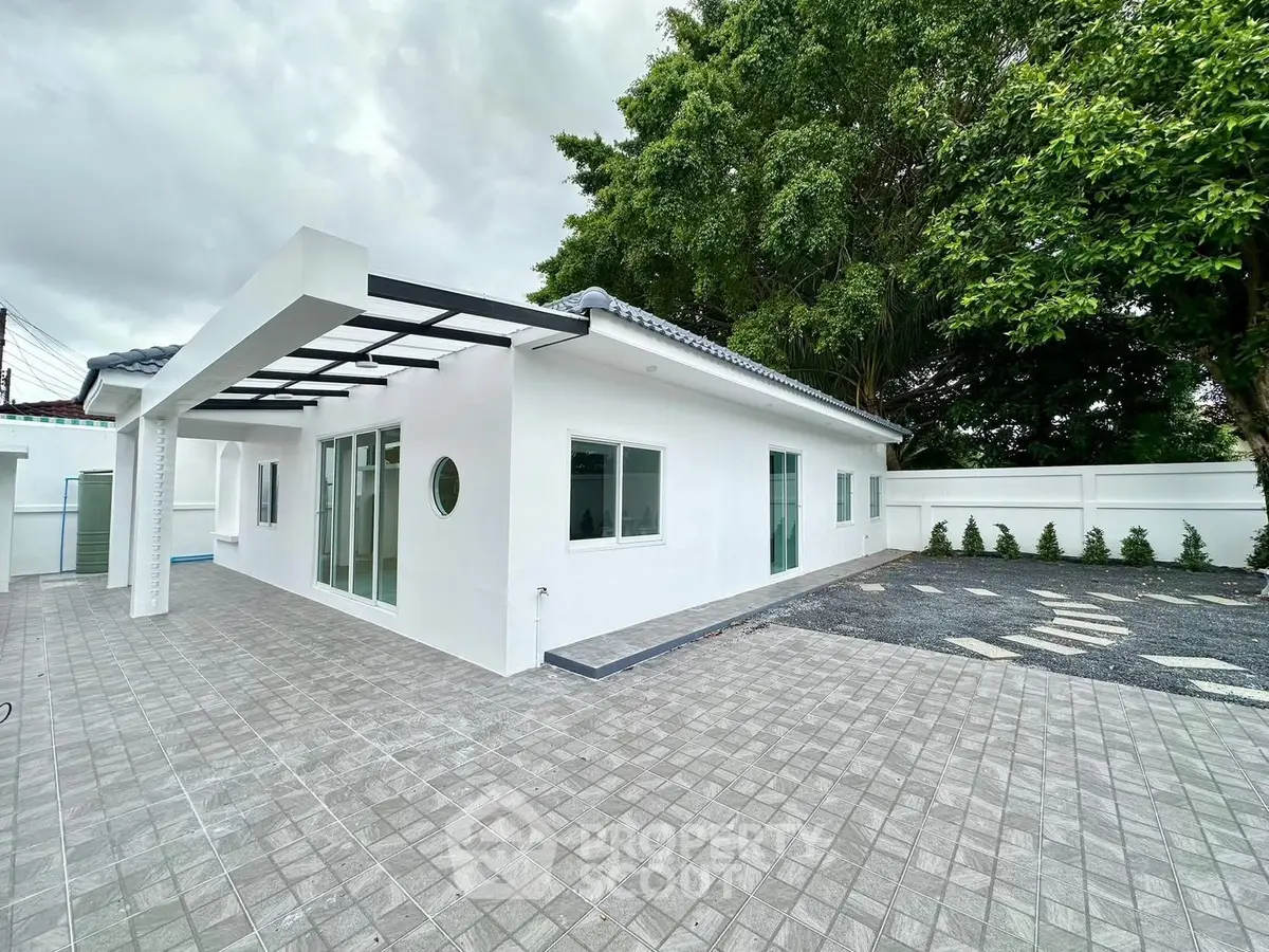 Modern white exterior house with spacious patio and lush greenery