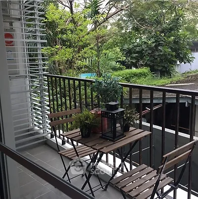 Charming balcony with lush greenery view, perfect for relaxation and outdoor dining.