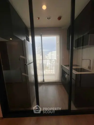 Modern kitchen with sleek design and city view, featuring glass doors and contemporary appliances.
