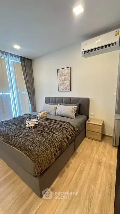 Modern bedroom with stylish decor and natural light, featuring a cozy bed and elegant furnishings.