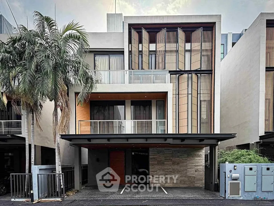 Modern architectural facade of a luxury townhouse with sleek design and palm tree landscaping.
