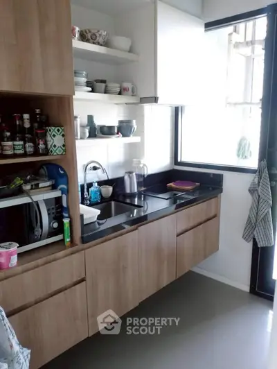 Modern kitchen with sleek cabinetry and ample natural light, featuring a compact and efficient layout.