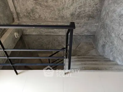 Modern industrial staircase with sleek metal railing and concrete walls
