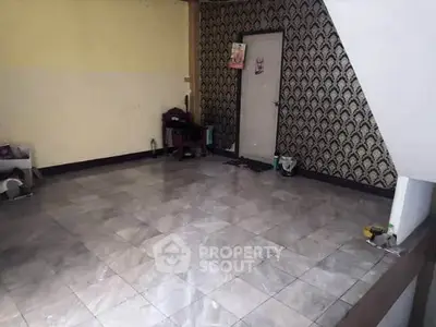 Spacious tiled room with patterned wallpaper and minimal furnishings