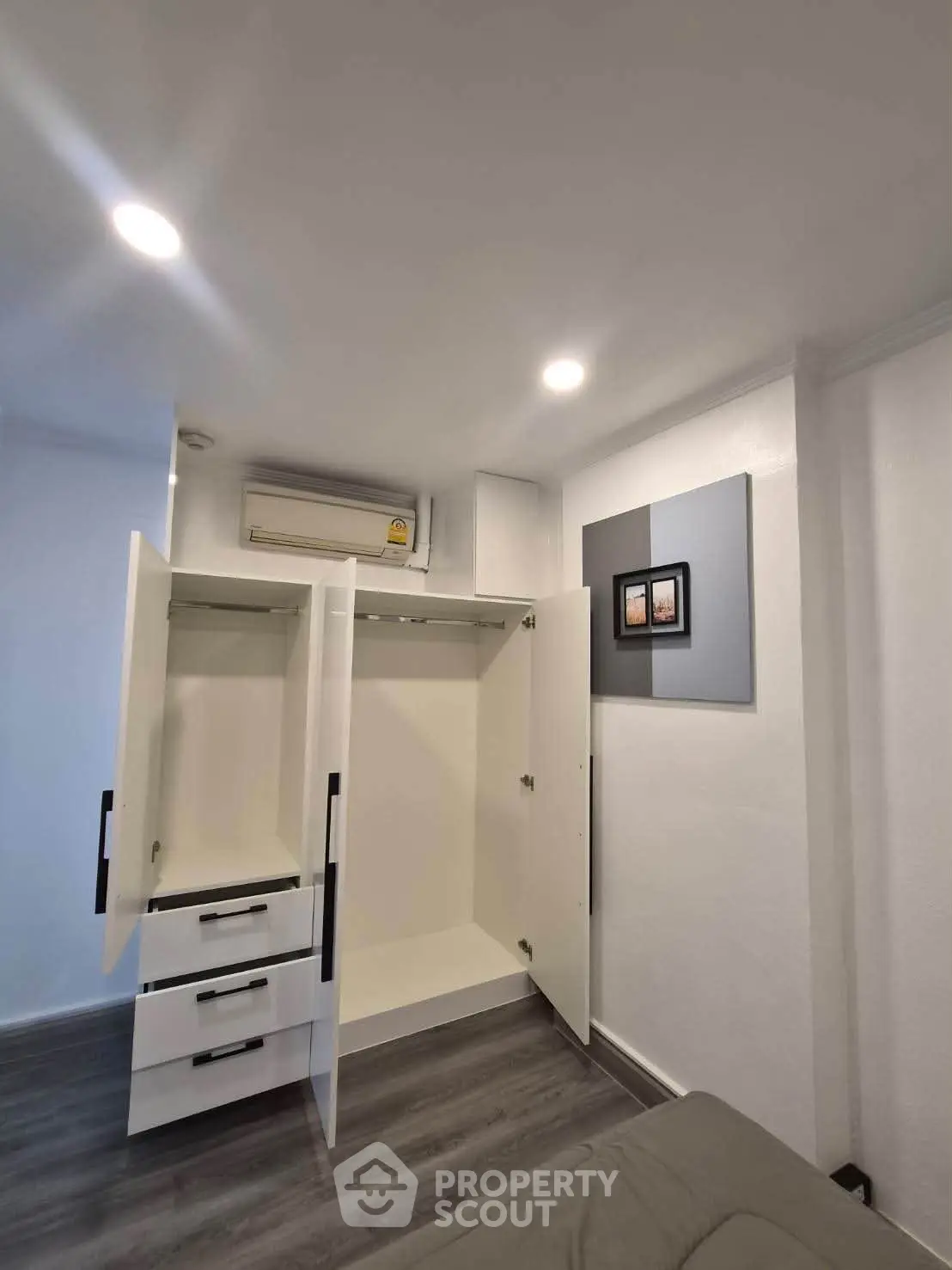 Modern bedroom with open wardrobe and air conditioning unit, showcasing sleek design and ample storage space.