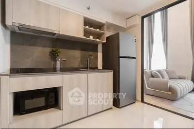 Modern kitchen with sleek cabinetry and open layout next to cozy living area.