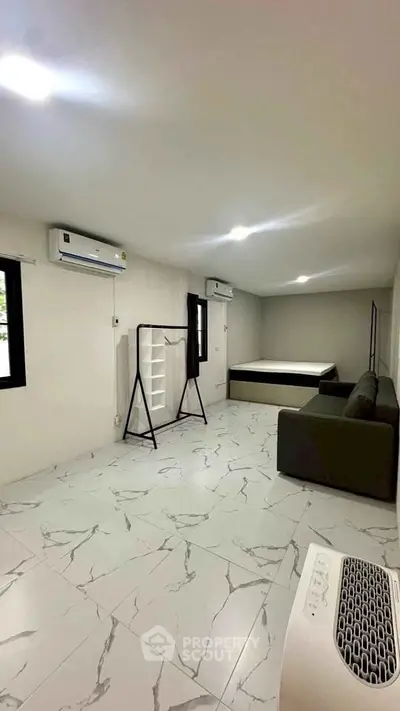 Spacious bedroom with modern furnishings and air conditioning, featuring elegant marble flooring.