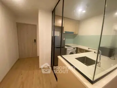 Modern kitchen with glass partition, sleek cabinetry, and built-in appliances in a compact layout.