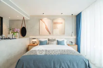 Modern bedroom with stylish decor, large window, and cozy bedding in a bright apartment.