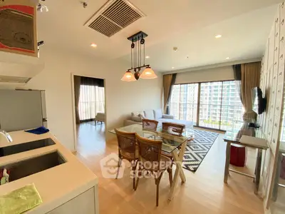 Spacious open-plan living room with modern kitchen and large windows offering city views.