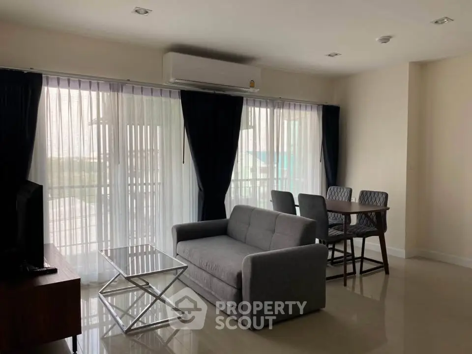 Modern living room with sleek furniture and large windows offering natural light.