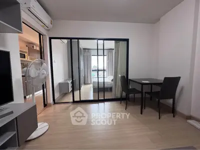 Modern apartment interior with open layout, featuring a bedroom view through glass doors and a cozy dining area.