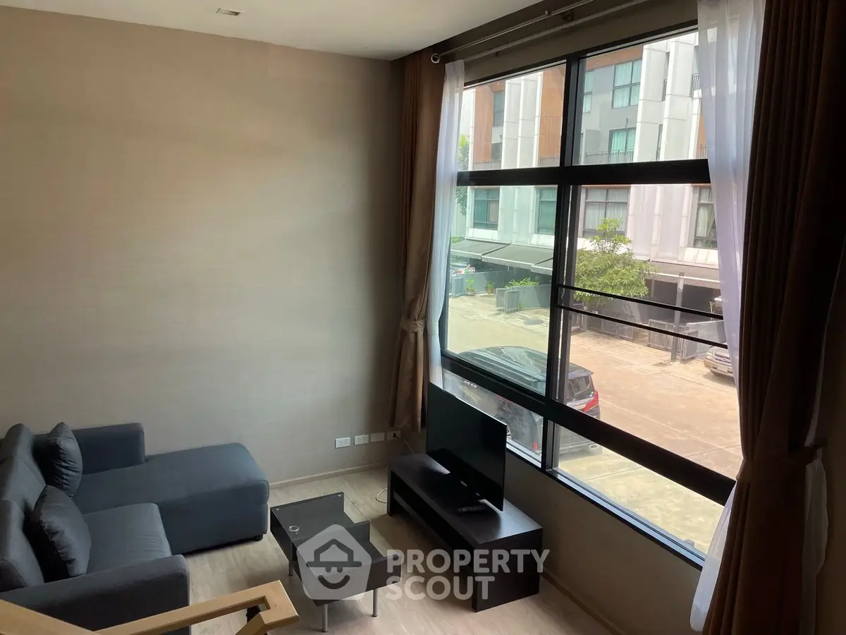 Modern living room with large window and stylish furniture in urban apartment