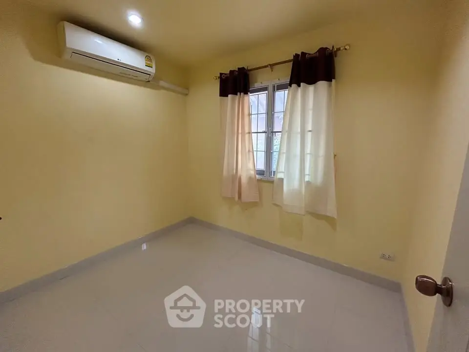 Spacious empty room with air conditioning and window curtains, ideal for customization.
