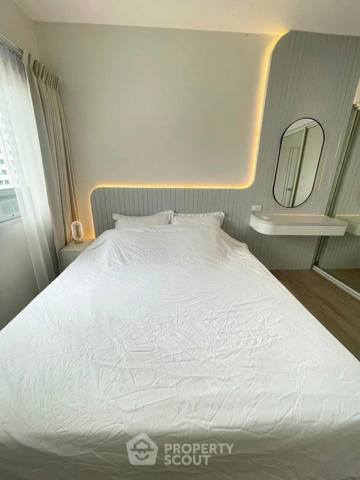 Modern bedroom with stylish lighting and mirror, featuring a cozy bed and elegant decor.