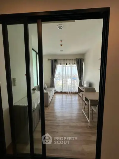 Modern living room with wooden flooring and large window offering city view