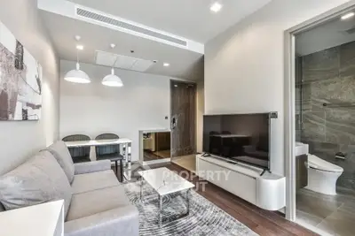 Modern living room with sleek design and adjacent bathroom, featuring contemporary furniture and decor.