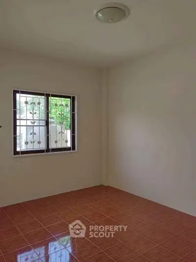 Spacious empty room with tiled floor and window view, perfect for customization.