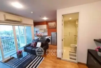 Modern apartment with open living room and kitchen, featuring a balcony view and stylish decor.