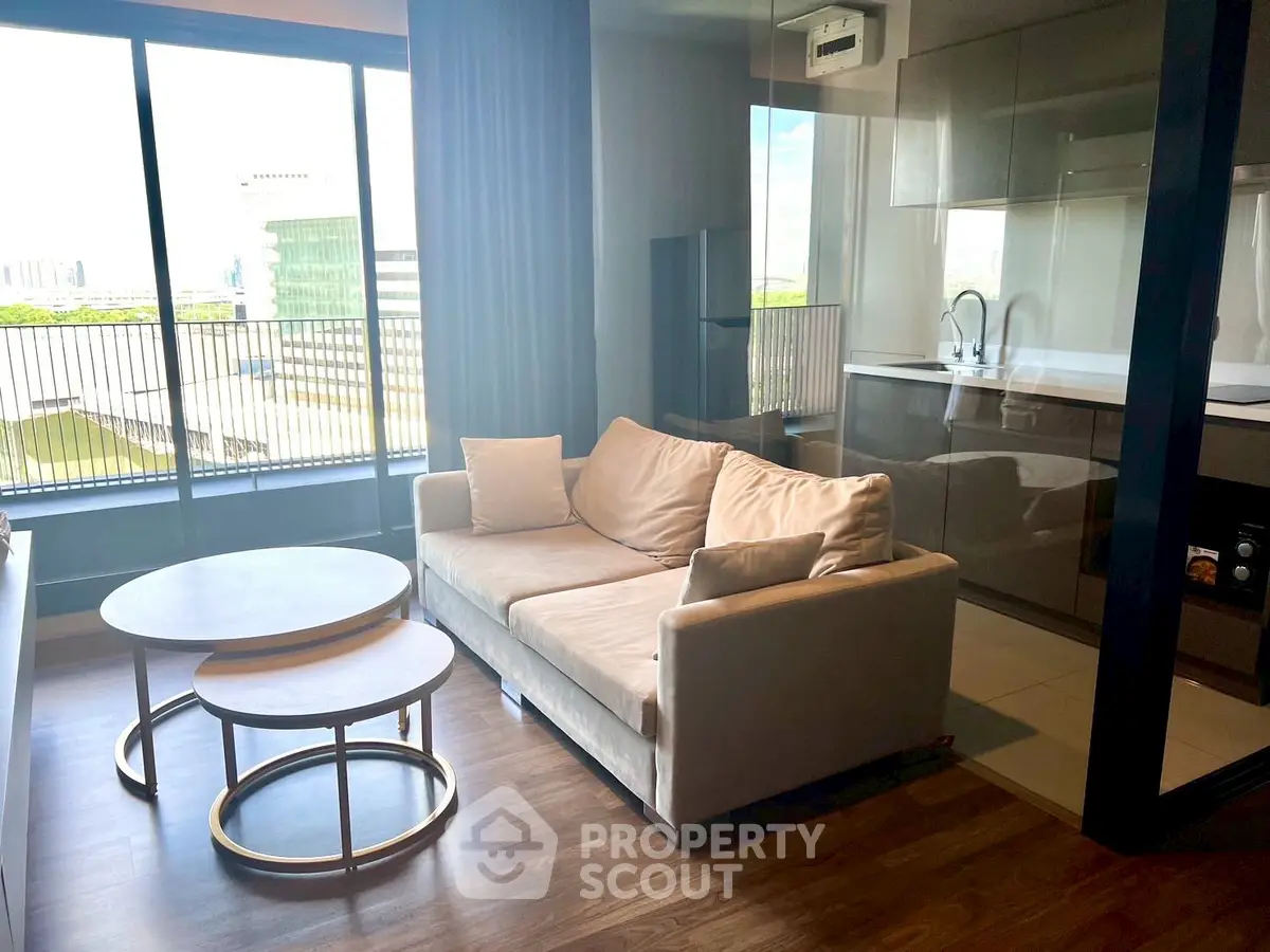 Modern living room with cozy sofa and open kitchen, featuring large windows and a balcony view.