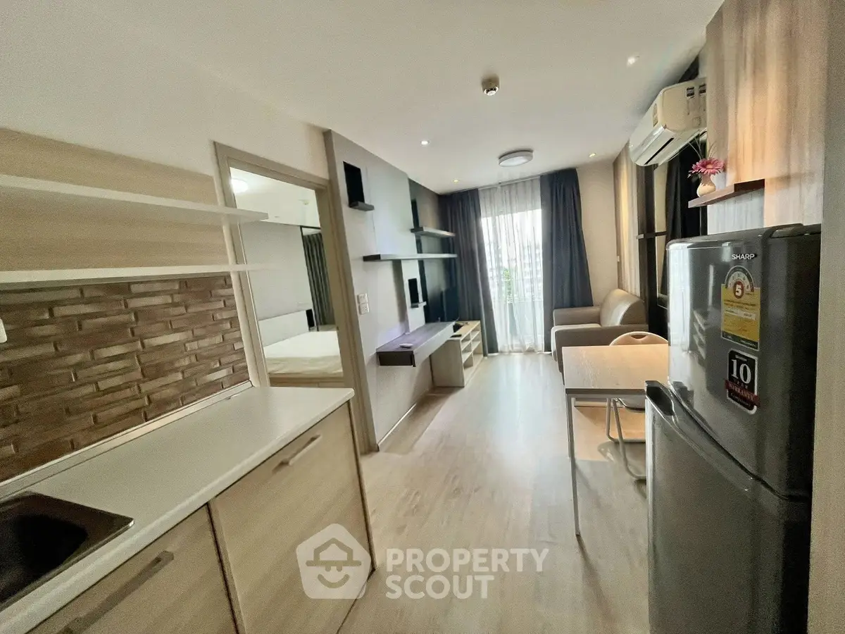 Modern open-plan living room with kitchen and balcony access in stylish apartment.
