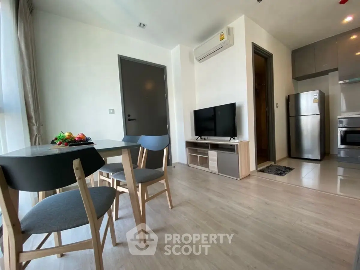 Modern living room with dining area and kitchen, featuring sleek furniture and appliances.