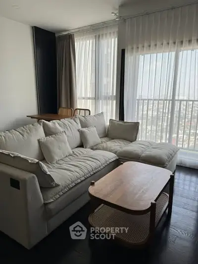Modern living room with cozy sectional sofa and city view through large windows.