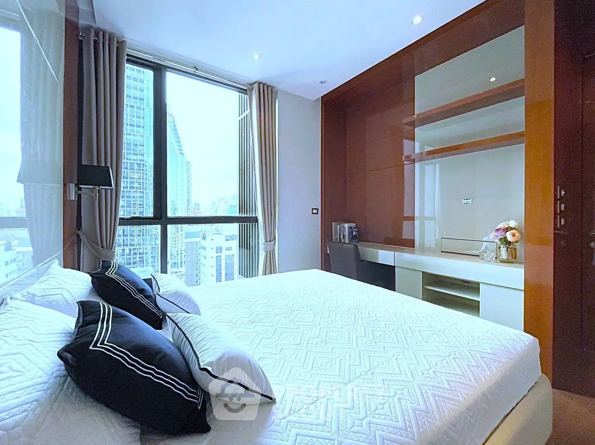 Luxurious bedroom with city view, modern decor, and elegant furnishings in high-rise apartment.