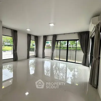 Spacious corner unit living room with large windows and garden view