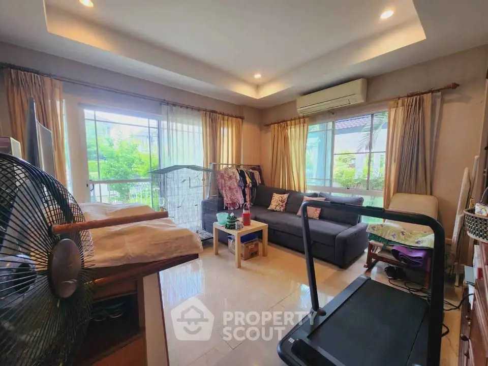 Spacious living room with modern decor and large windows offering natural light and garden views.