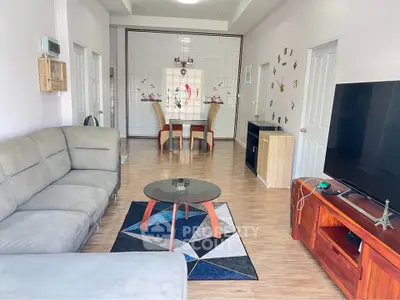 Spacious living room with modern decor and large TV, perfect for relaxation and entertainment.