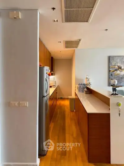 Modern kitchen with sleek wooden cabinets and stainless steel appliances in a stylish apartment.