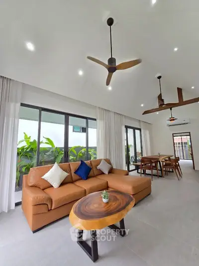 Spacious modern living room with elegant decor and large windows overlooking greenery.