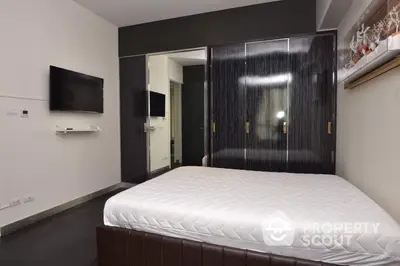 Sleek modern bedroom with a large comfortable bed, wall-mounted TV, and mirrored wardrobe, perfect for contemporary living.