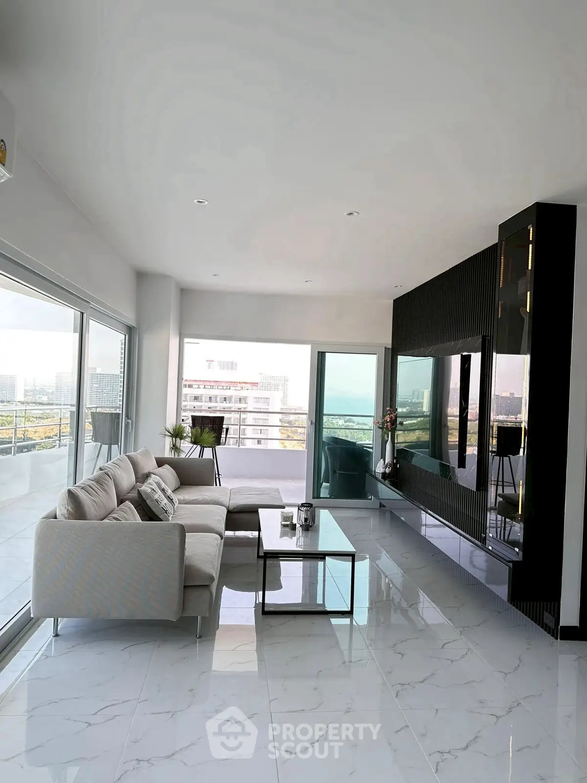 Spacious modern living room with panoramic city view and elegant decor.