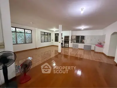 Spacious open-plan living area with wooden flooring and modern kitchen.