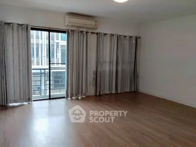 Spacious empty living room with wooden flooring and large windows for natural light.