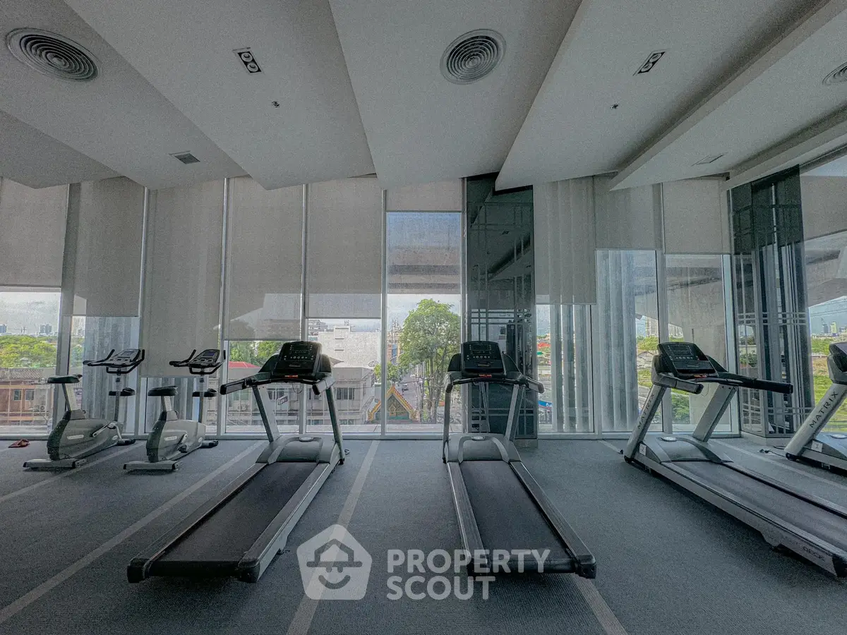 Spacious gym with modern treadmills and city view, perfect for fitness enthusiasts.